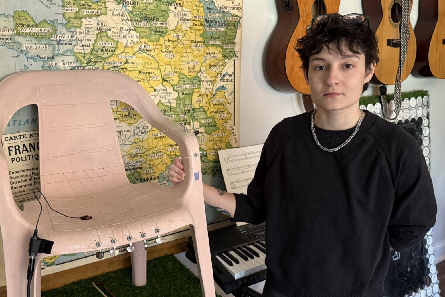 person stands next to monobloc chair converted into an instrument with harp strings