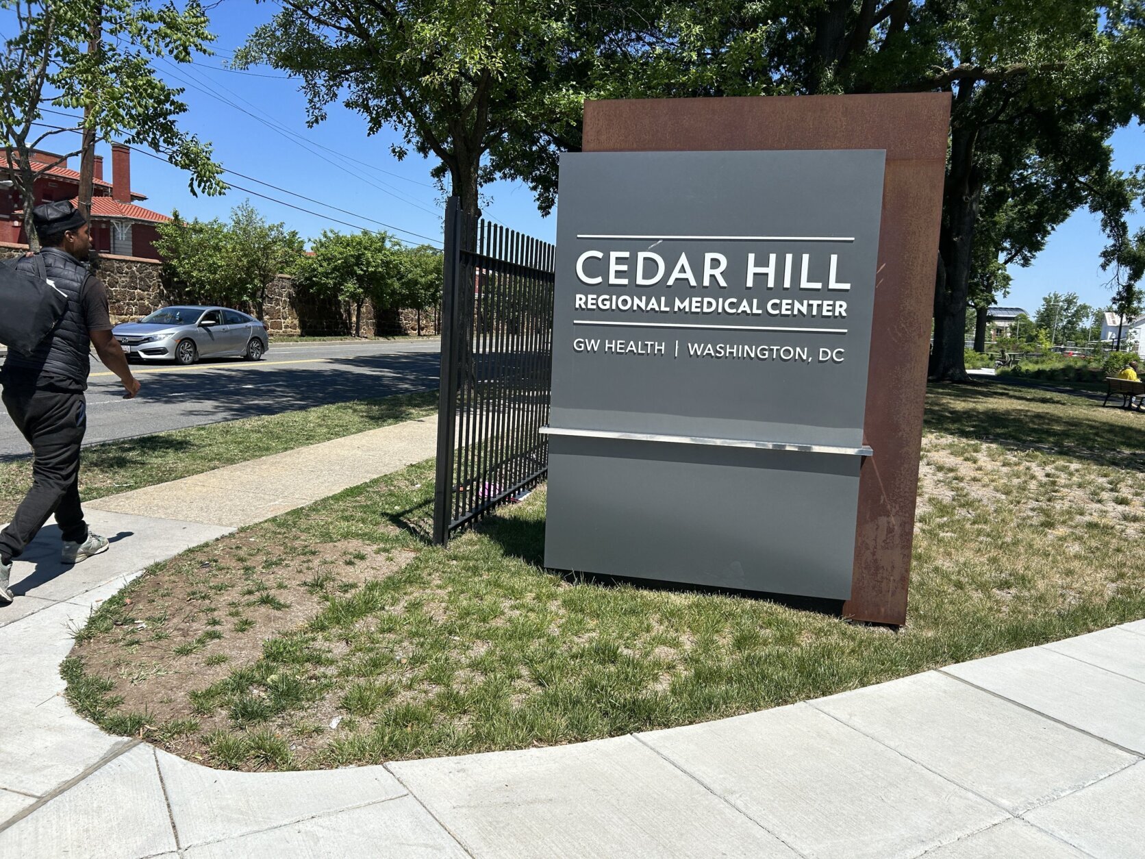 A sign reading "Cedar Hill Regional Medical Center" sits in the middle of a lawn at the confluence of two concrete pathways.