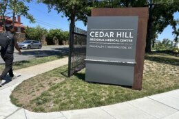 A sign reading "Cedar Hill Regional Medical Center" sits in the middle of a lawn at the confluence of two concrete pathways.