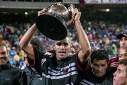soccer player holds up trophy