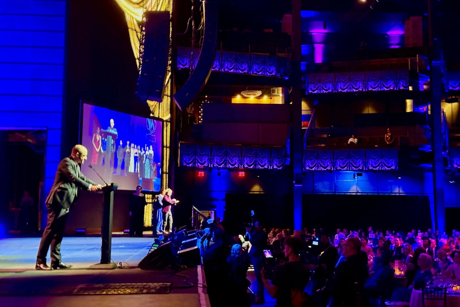 speaker on stage at award show in theatre
