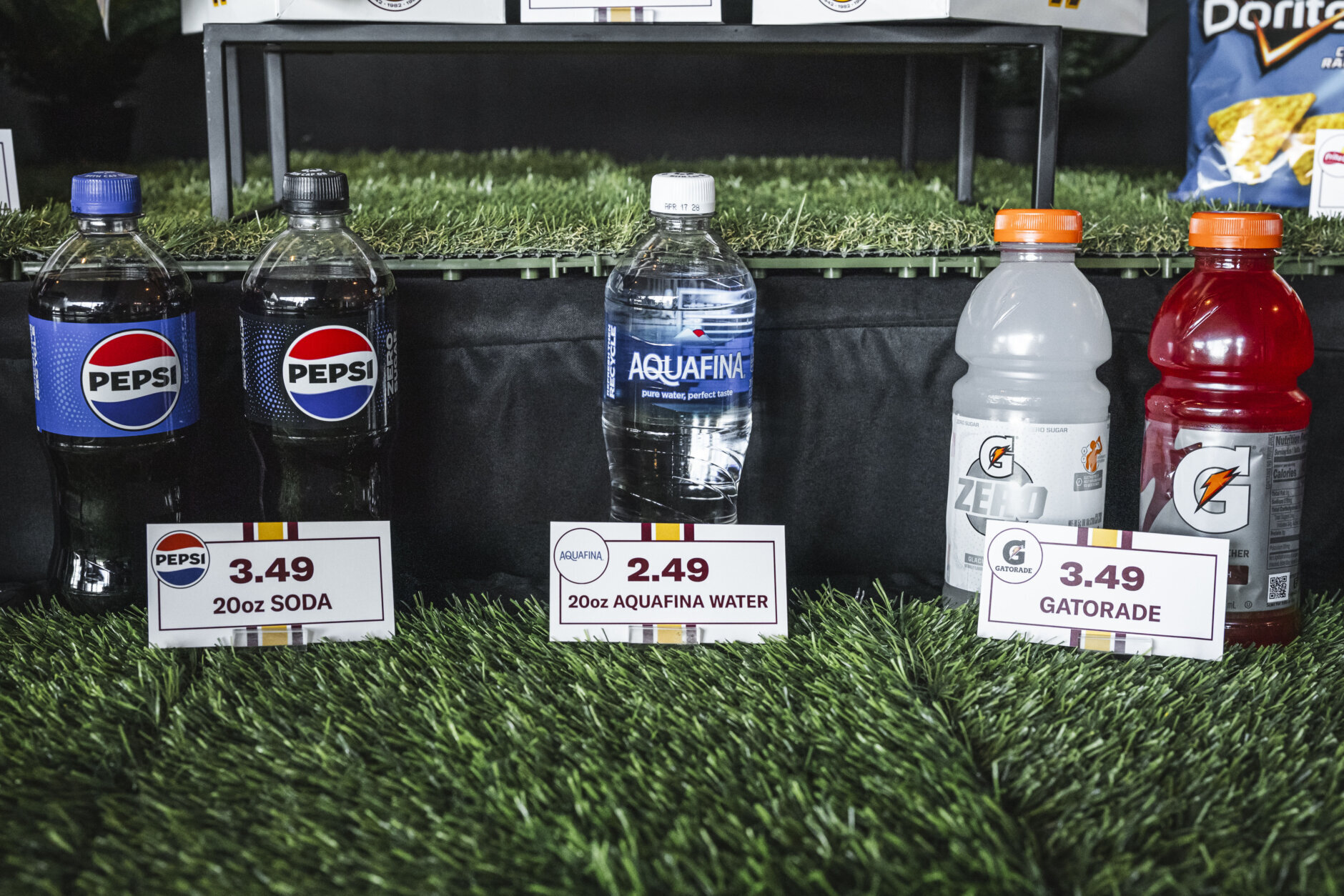 Bottles of Pepsi soda, Dasani water, grey Gatorade and red Gatorade sit arranged on a bed of turf at a Washington Commanders press conference