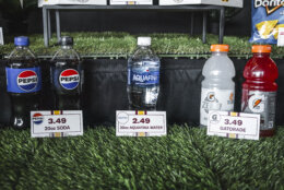 Bottles of Pepsi soda, Dasani water, grey Gatorade and red Gatorade sit arranged on a bed of turf at a Washington Commanders press conference