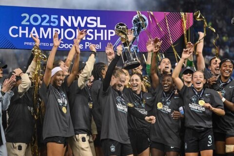 FILE - NJ/NY Gotham FC defender Emily Sonnett, center, lifts the NWSL championship trophy after defeating the Washington Spirit in an NWSL women's championship soccer match Nov. 22, 2025, in San Jose, Calif. (AP Photo/Justine Willard, File)