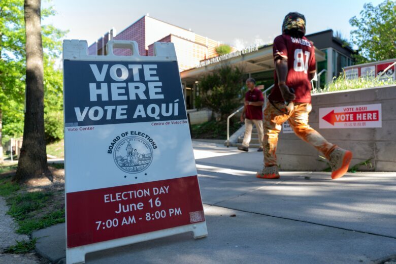 people stream into polling place for election with sign saying vote here