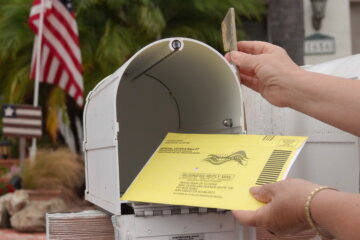 hand putting ballot into mailbox