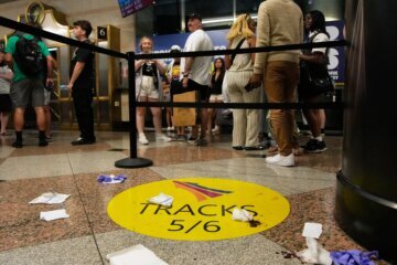 People stand near an area roped off after a stabbing at Penn Station