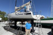 a man in a blue polo stands beneath a large sailboat