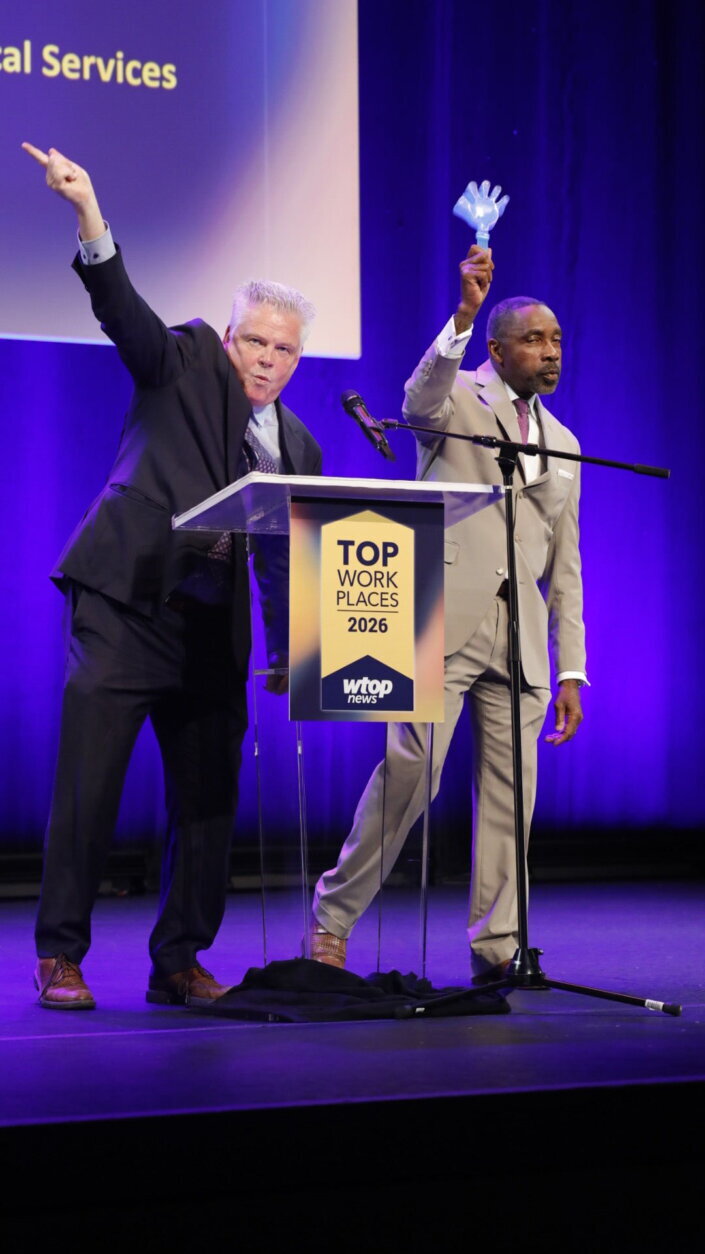 two men speaking at a podium on stage