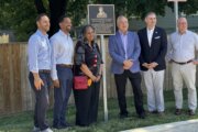 people stand by newly unveiled plaque for photo opp