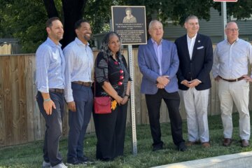 people stand by newly unveiled plaque for photo opp