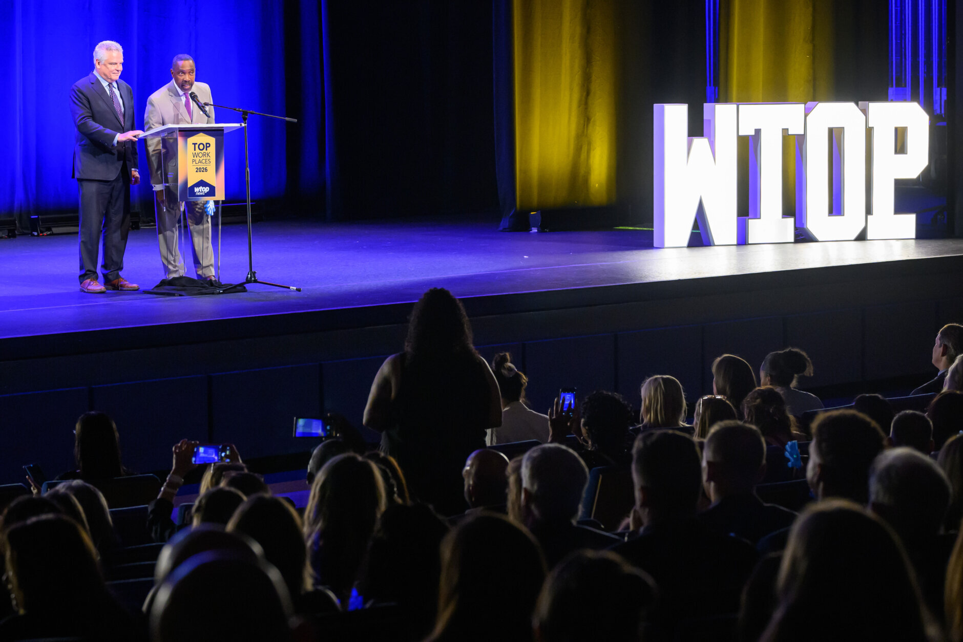 two people standing on stage from far away
