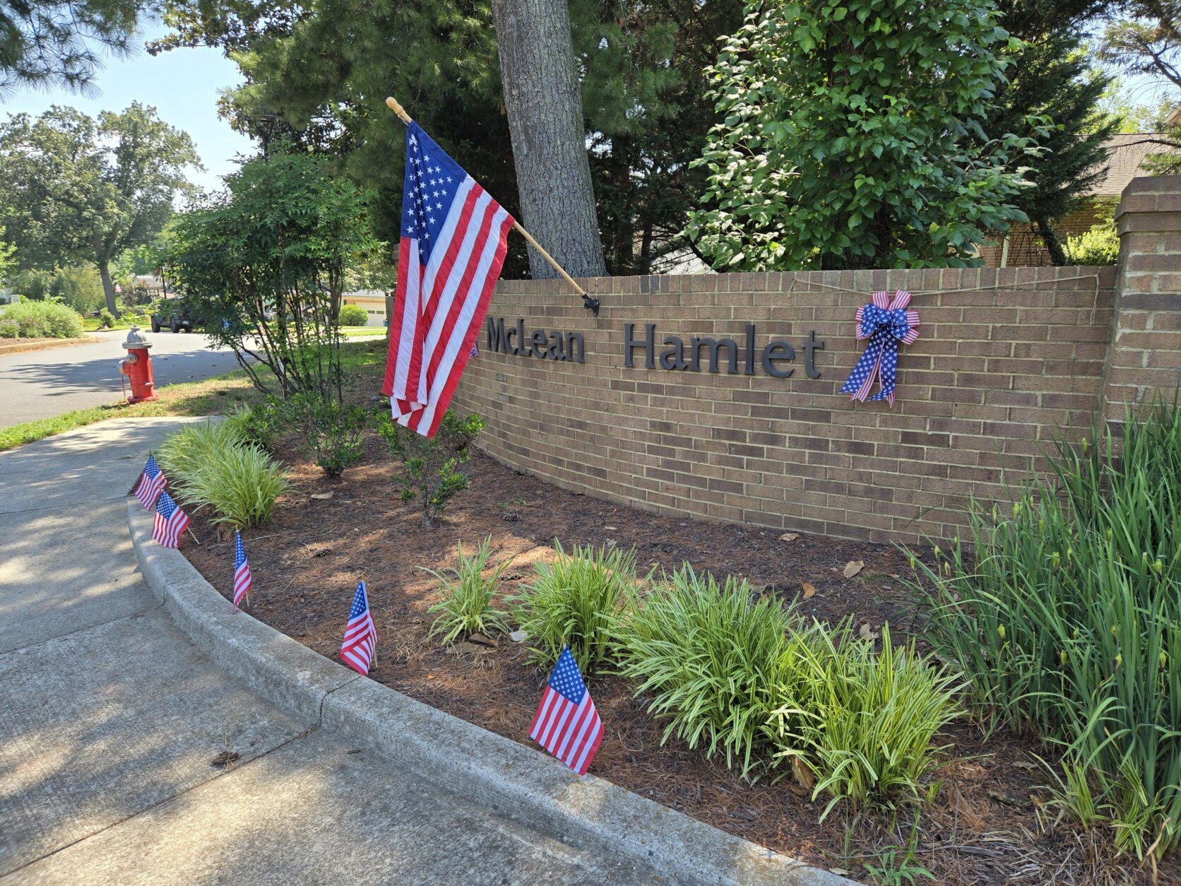 A flag hangs over a brick wall welcoming visitors to McLean Hamlet.