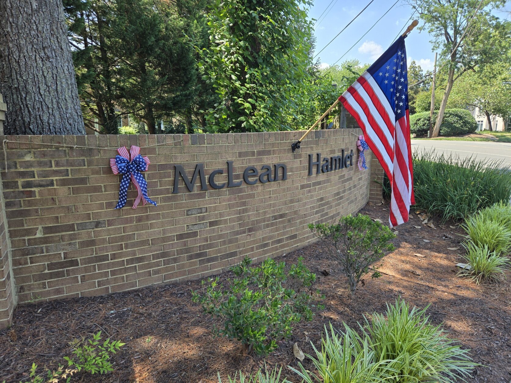 An alternate angle shows a flag and patriotic ribbon at the gates of McLean Hamlet.