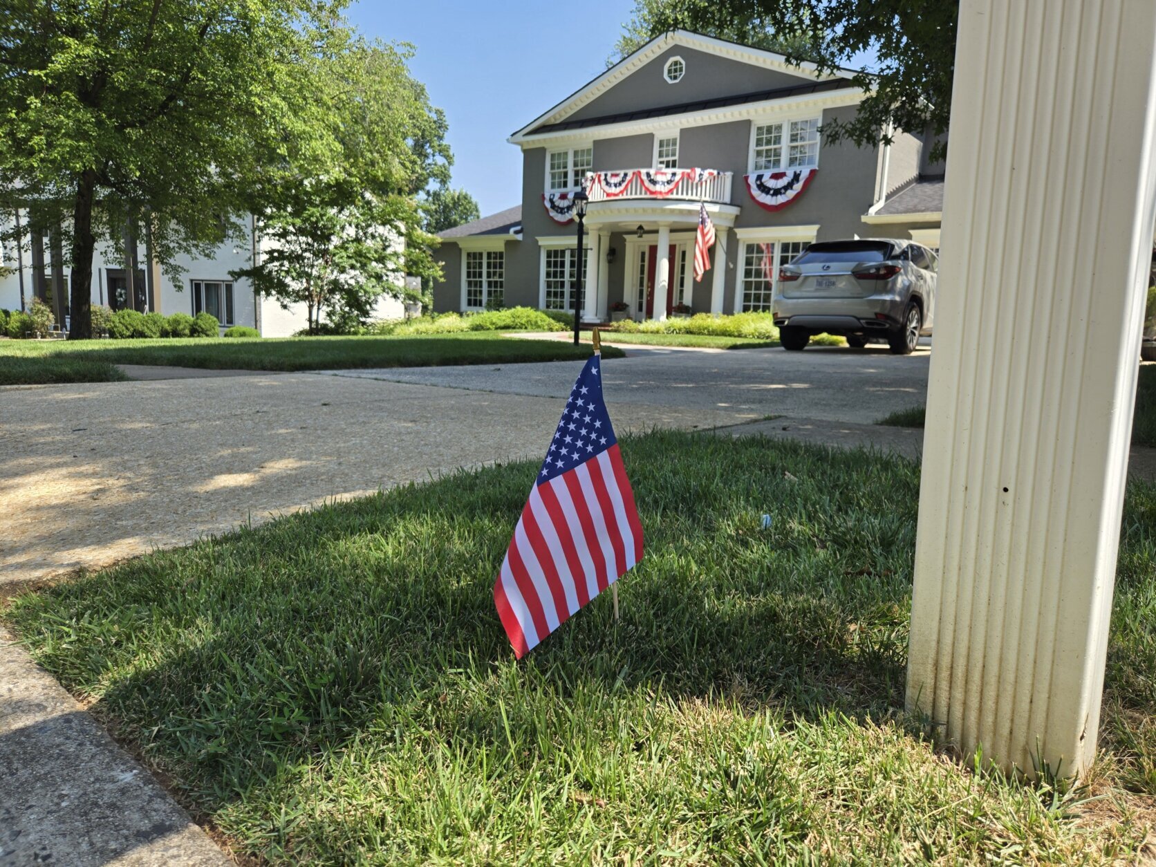 A stick-flag protrudes from a small and grassy quad at the driveway of a McLean Hamlet home.