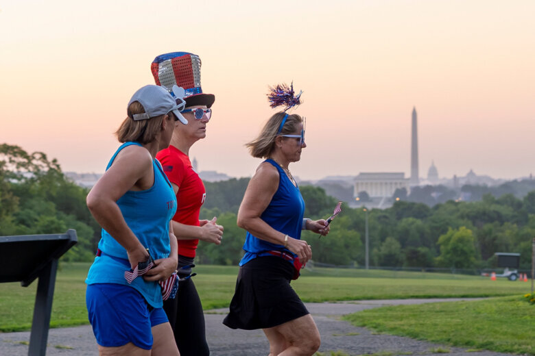 Runners wearing Independence Day-themed items jog at dawn past an overlook in Arlington, Va., as Washington prepares for sweltering temperatures, Friday, July 3, 2026. (AP Photo/J. Scott Applewhite)