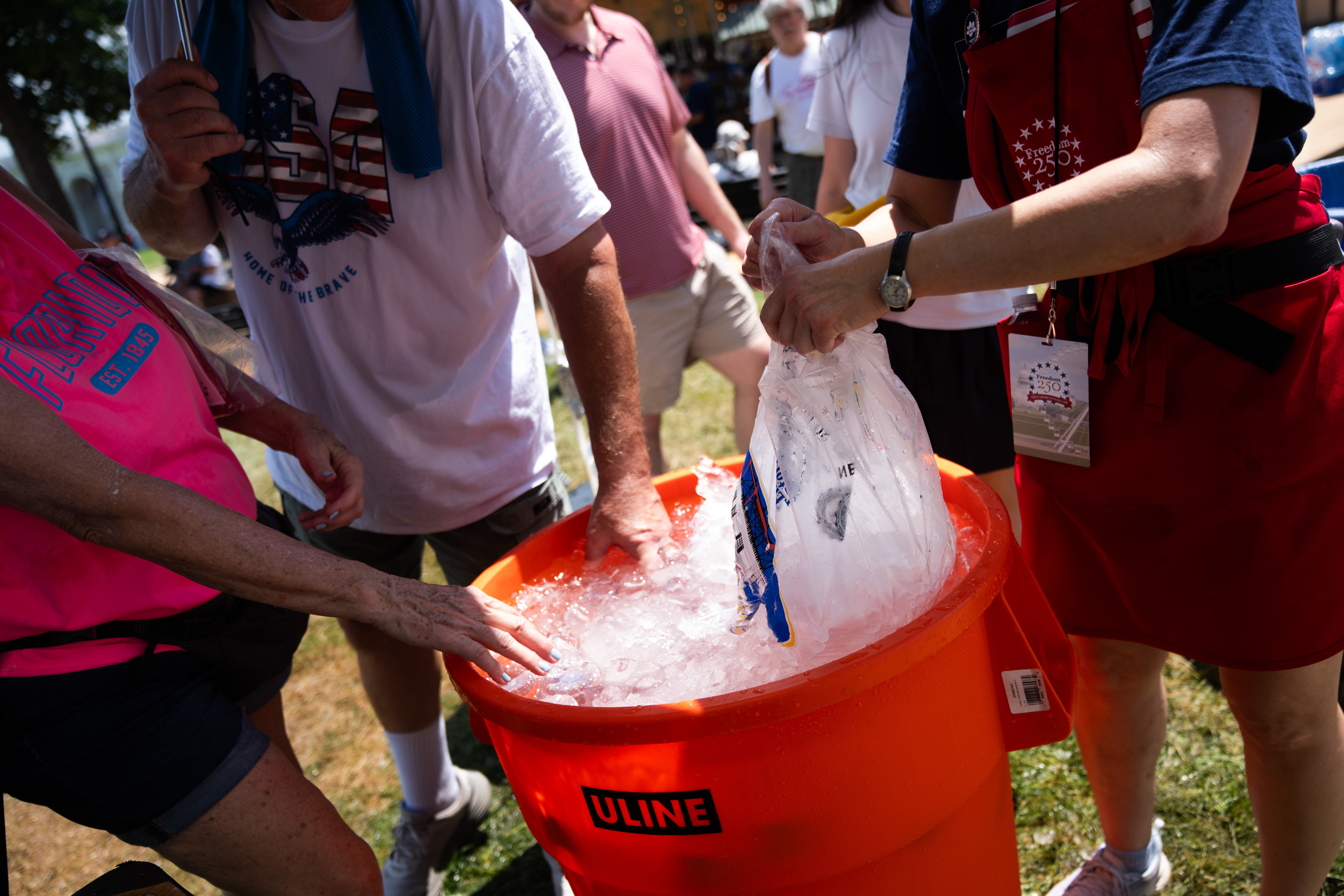 Attendees dip their hands in ice water at the Great American State Fair on the National Mall, Friday, July 3, 2026, in Washington. (AP Photo/Allison Robbert)