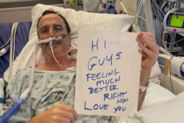 peterson holds sign up in hospital bed that reads "hi guys feeling much better right now love you"