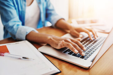a woman types on a laptop keyboard