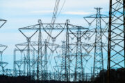 Electrical pylons and power cables dominating rural farmland scene.