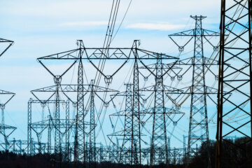 Electrical pylons and power cables dominating rural farmland scene.