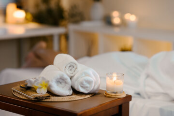 A spa room with rolled towels and lit candle on a table