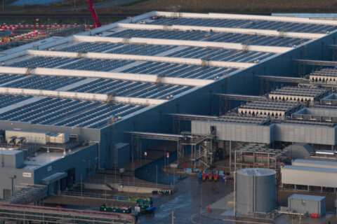 Aerial drone video of a large data center building exterior, representing the massive technological infrastructure required for storing, processing data, and delivering global digital services.