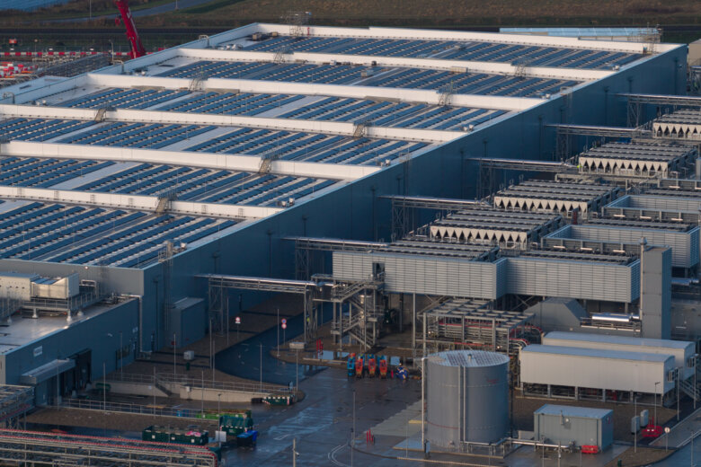 Aerial drone video of a large data center building exterior, representing the massive technological infrastructure required for storing, processing data, and delivering global digital services.