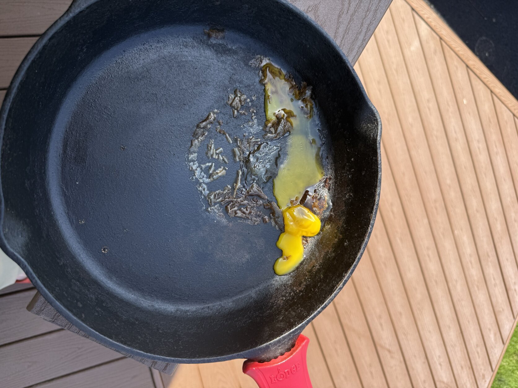A cast-iron pan of molten egg sits on a patio deck.