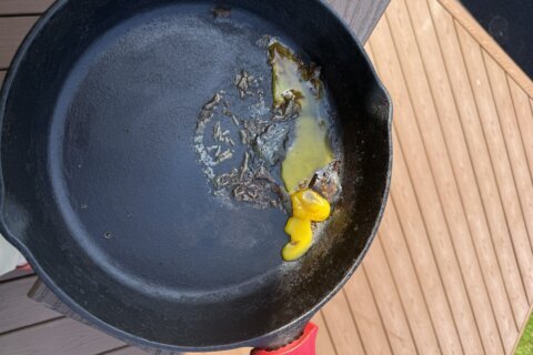 A cast-iron pan of molten egg sits on a patio deck.