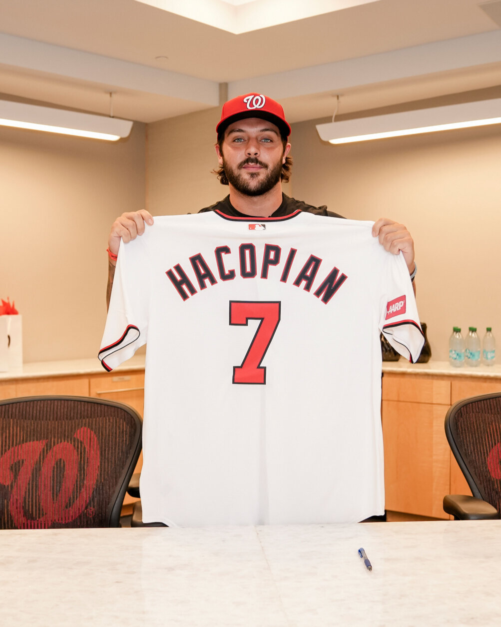 baseball player holds up jersey in room