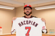 baseball player holds up jersey in room