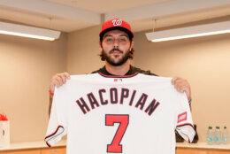 baseball player holds up jersey in room