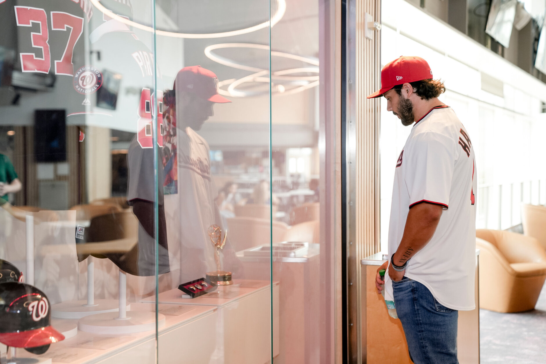 baseball player looks into glass case of accolades, side view