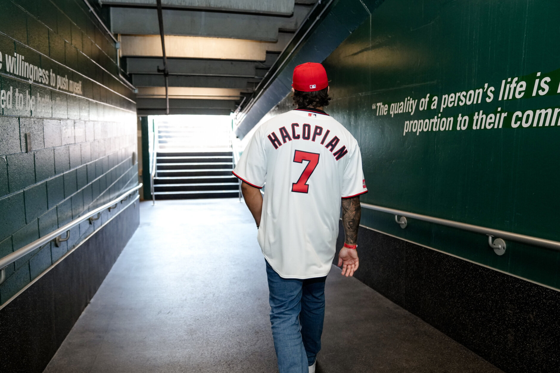baseball player with back to camera walks down tunnel on way to field