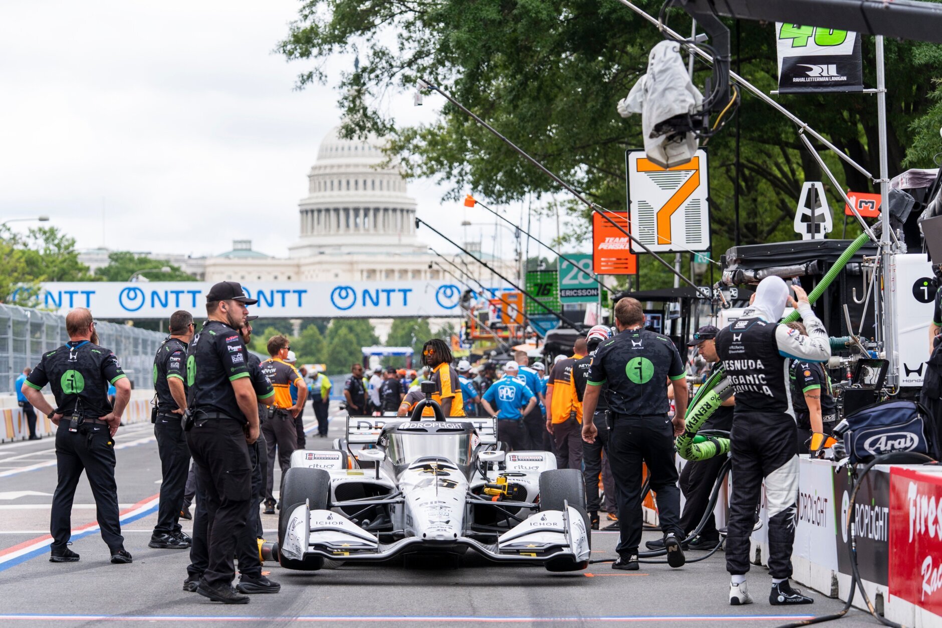 Race car drivers and pit crew members prepare to take practice runs
