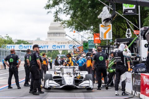Race car drivers and pit crew members prepare to take practice runs