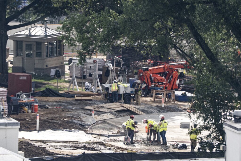 Crews remove the granite seal on the White House helipad, signaling potential project delays