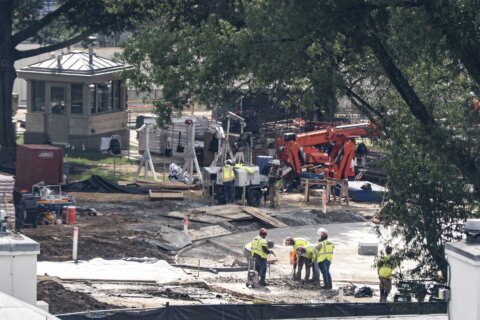 Crews remove the granite seal on the White House helipad, signaling potential project delays