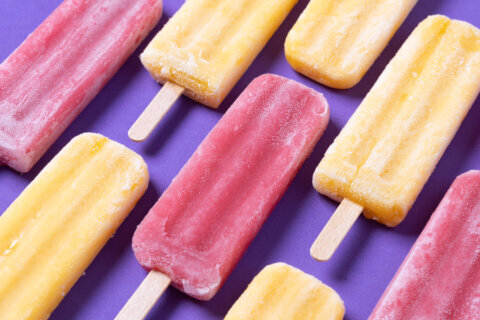 Red strawberry popsicles and yellow popsicles on purple background
