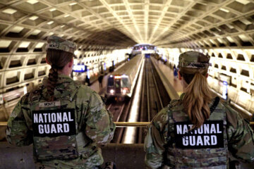 national guard troops faced away from camera overlooking metrorail station platform