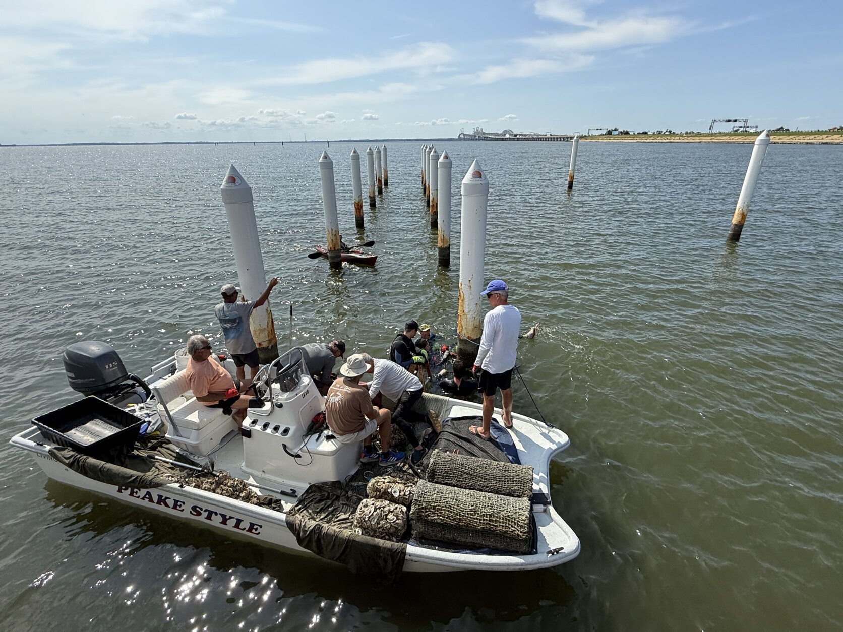 Six guys in a boat weighed down by more than 30 bags full of oyster shells