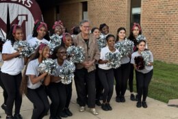 cheer leaders pose in group photo with a school official