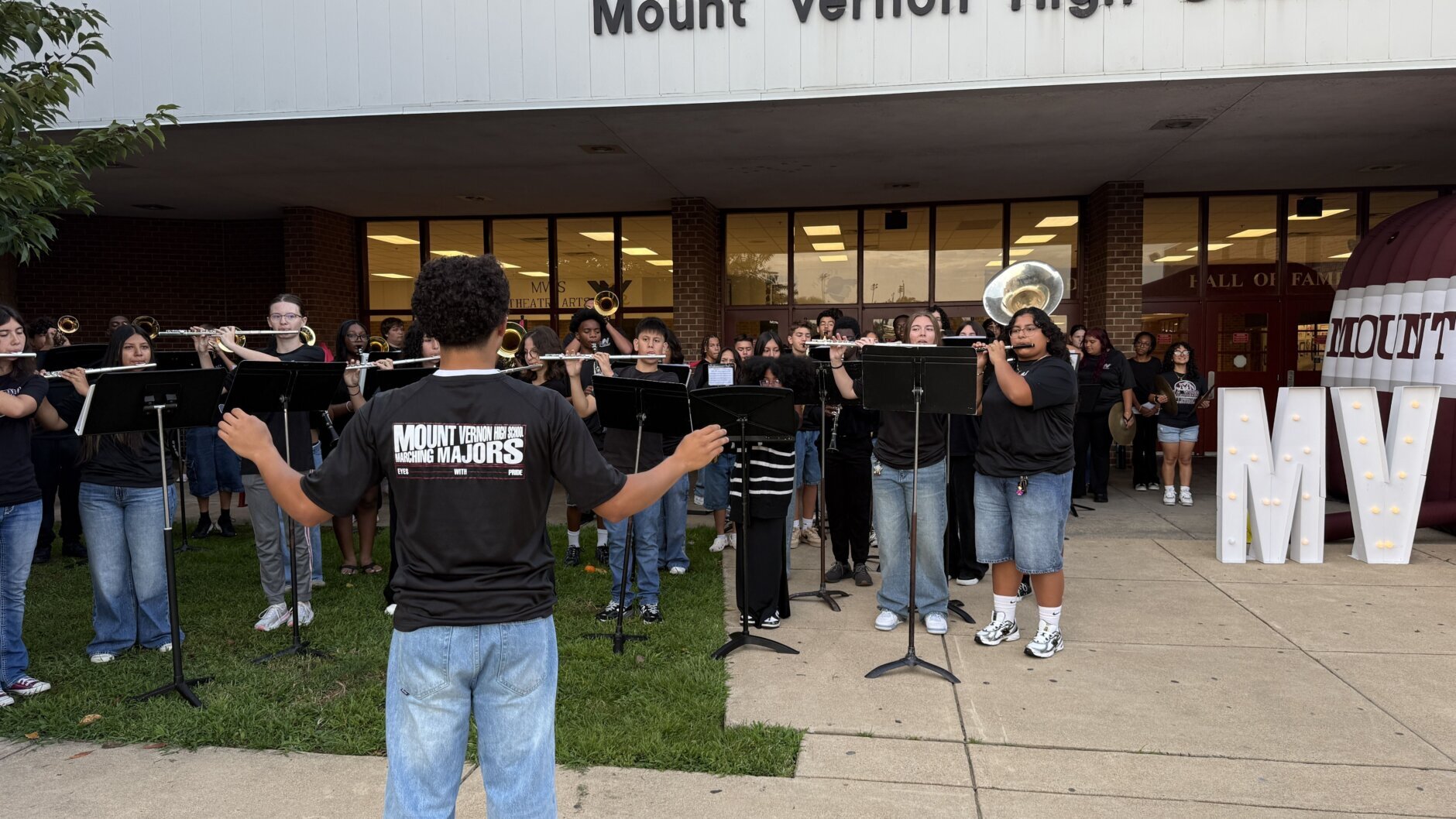school band performs in front of high school in casual wear