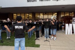 school band performs in front of high school in casual wear