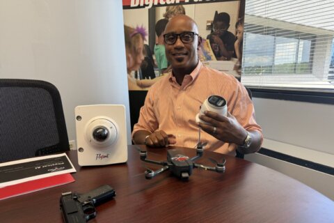 man holding camera security technology while sitting at wood table
