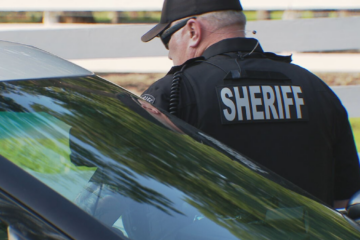 Fauquier County Sheriff's Office official next to vehicle.